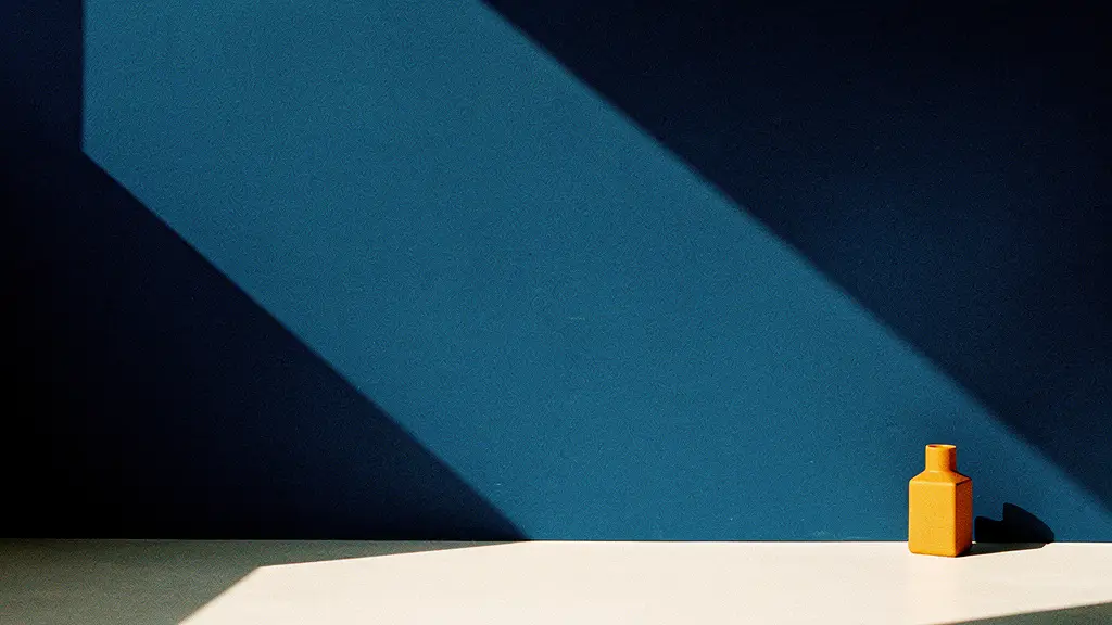 A narrow blade of sunlight crossing a dark navy corner, one small amber object at the far edge.