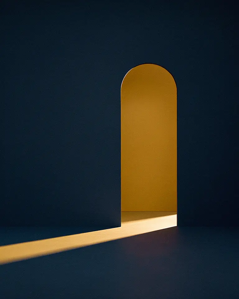 An arched opening in a deep navy wall, a wedge of warm amber sunlight falling through it onto the floor.