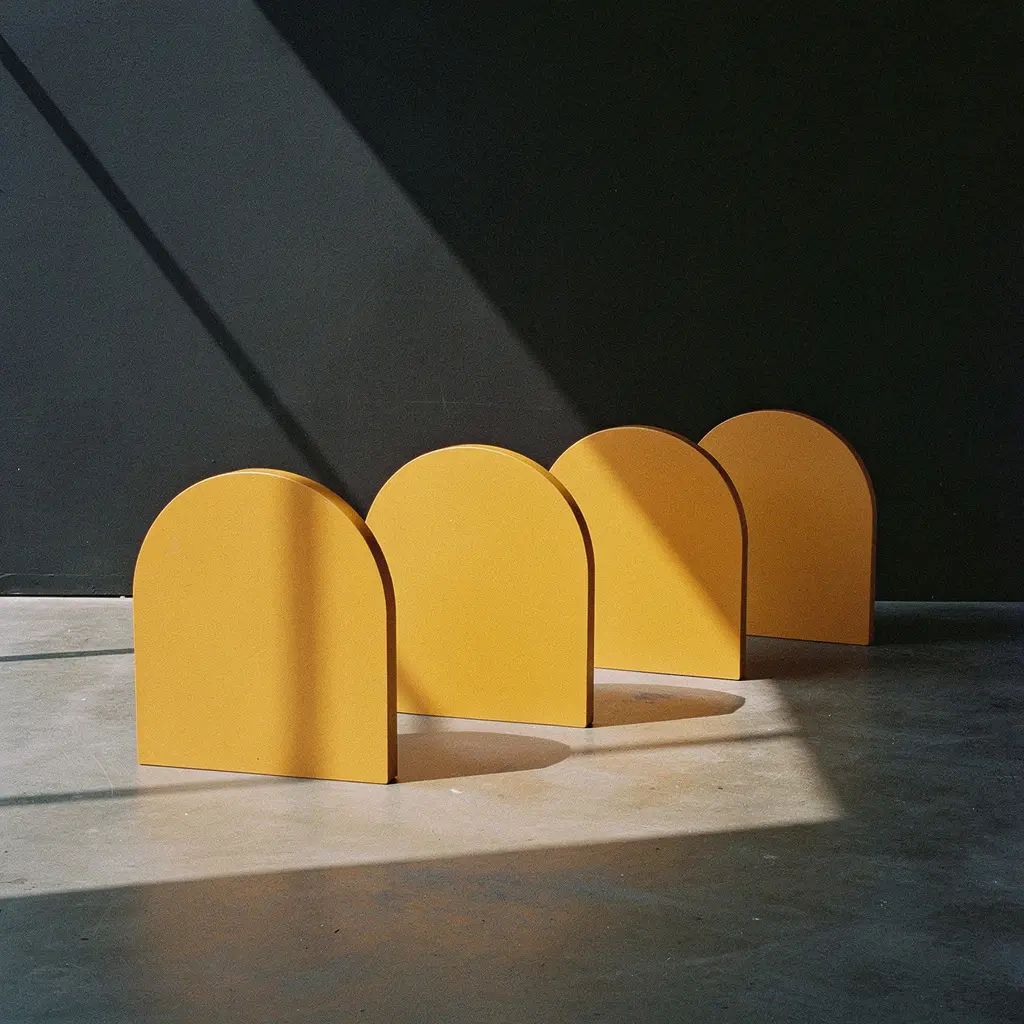 Four amber arch forms in a row against a dark wall, each casting its own hard shadow.